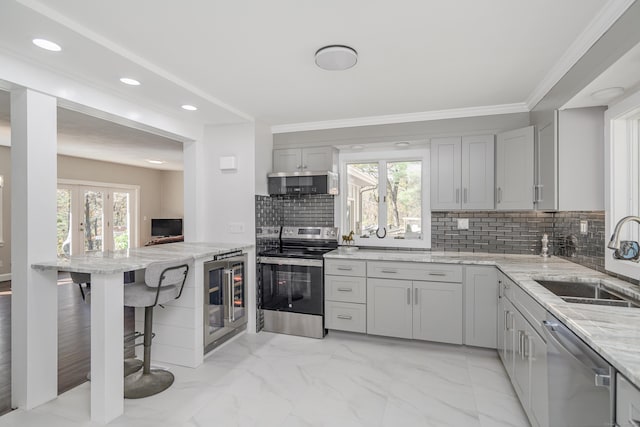 kitchen featuring sink, wine cooler, light stone countertops, tasteful backsplash, and stainless steel appliances