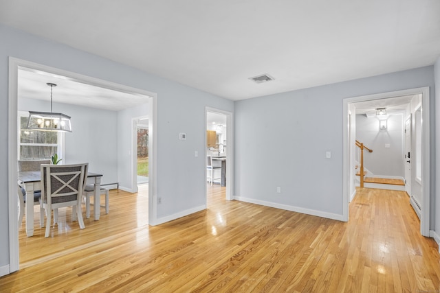 interior space featuring a healthy amount of sunlight, light wood-type flooring, baseboard heating, and a chandelier