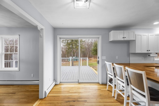 interior space featuring light wood-type flooring, white cabinetry, and baseboard heating