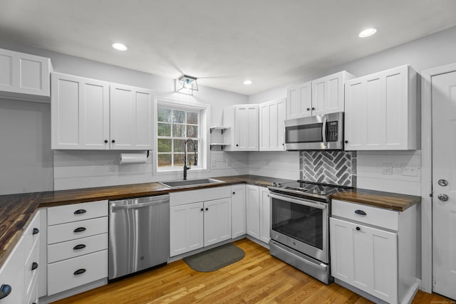 kitchen featuring wood counters, appliances with stainless steel finishes, white cabinetry, and sink