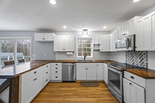 kitchen with butcher block countertops, white cabinetry, and appliances with stainless steel finishes