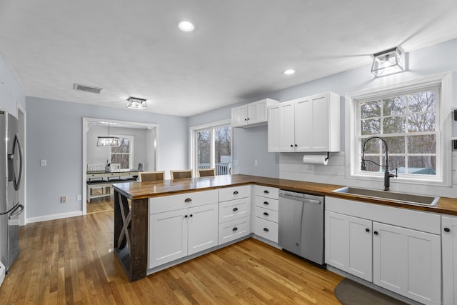 kitchen featuring butcher block countertops, white cabinetry, stainless steel appliances, and sink