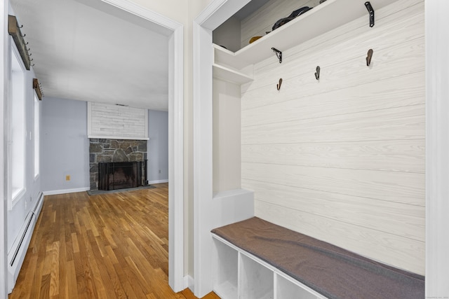 mudroom featuring hardwood / wood-style flooring, a stone fireplace, and baseboard heating