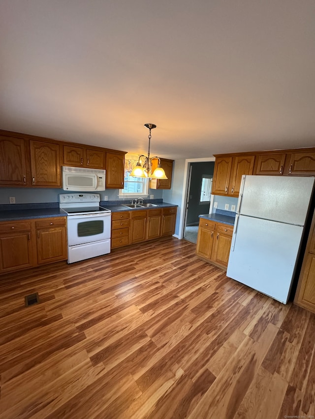 kitchen featuring hardwood / wood-style flooring, sink, a notable chandelier, decorative light fixtures, and white appliances