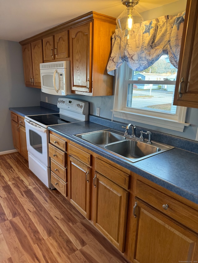 kitchen featuring sink, hardwood / wood-style floors, pendant lighting, and white appliances