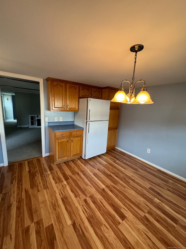 kitchen featuring hanging light fixtures, light hardwood / wood-style flooring, white fridge, and a notable chandelier