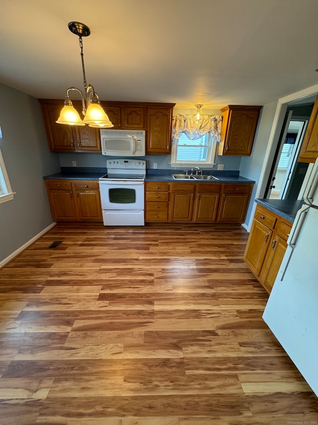 kitchen with white appliances, light hardwood / wood-style flooring, an inviting chandelier, and sink