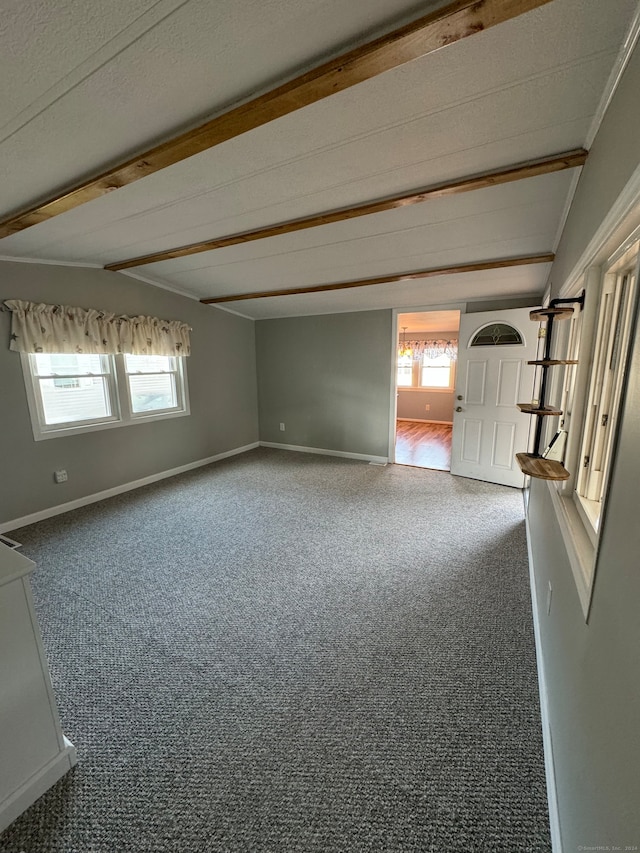 unfurnished room featuring carpet flooring, beamed ceiling, and plenty of natural light