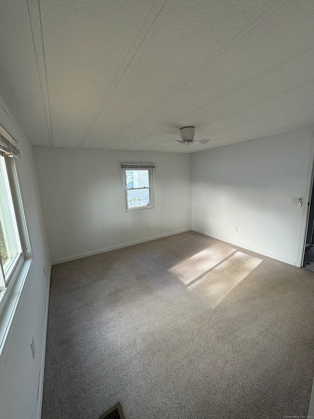 unfurnished room with ceiling fan, a healthy amount of sunlight, a textured ceiling, and carpet floors