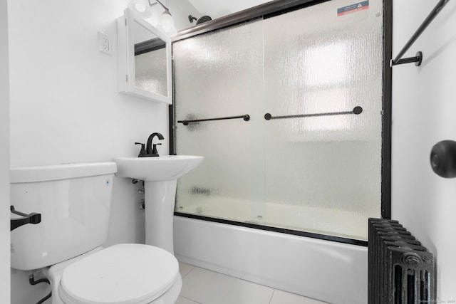 bathroom with tile patterned flooring, radiator heating unit, shower / bath combination with glass door, and toilet