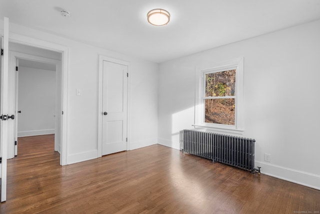 unfurnished bedroom featuring dark hardwood / wood-style flooring, a closet, and radiator heating unit