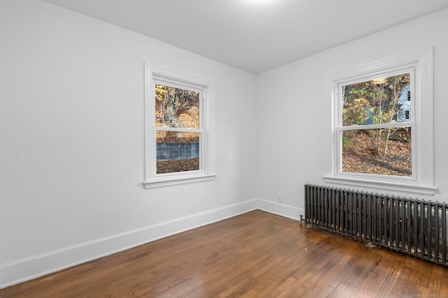 unfurnished room featuring radiator heating unit and dark hardwood / wood-style flooring