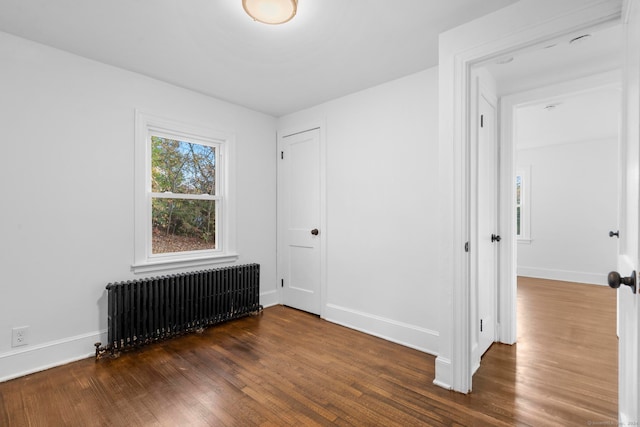 unfurnished room with dark wood-type flooring and radiator heating unit