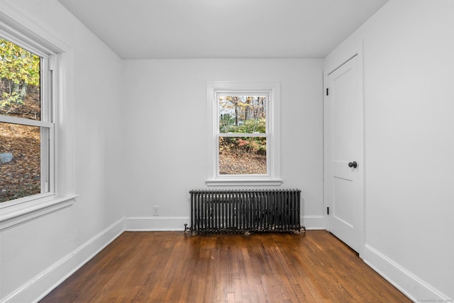 spare room with dark hardwood / wood-style flooring and radiator