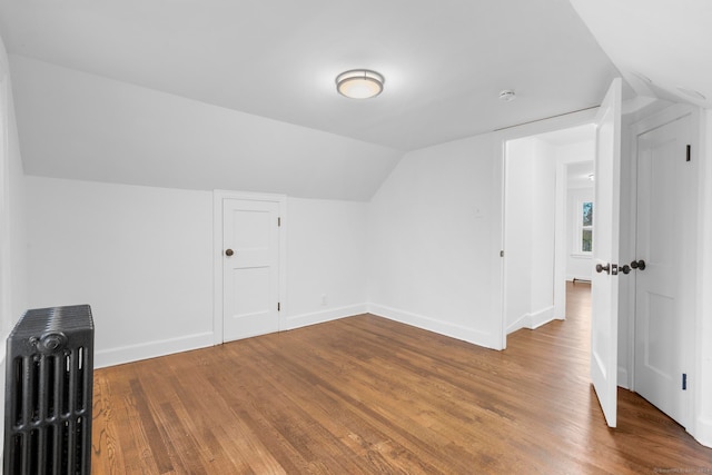 bonus room with hardwood / wood-style floors, radiator, and lofted ceiling