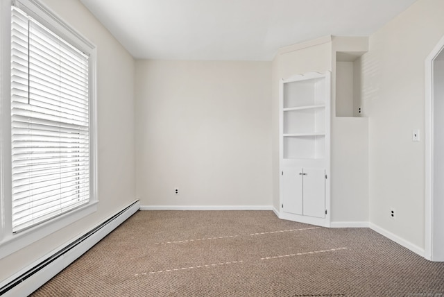 carpeted spare room with a wealth of natural light and a baseboard heating unit