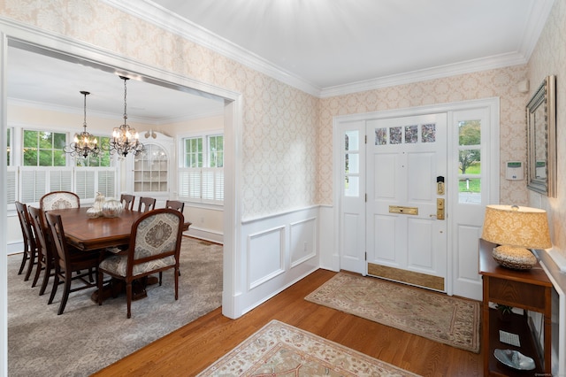 entrance foyer featuring hardwood / wood-style floors, plenty of natural light, ornamental molding, and a notable chandelier