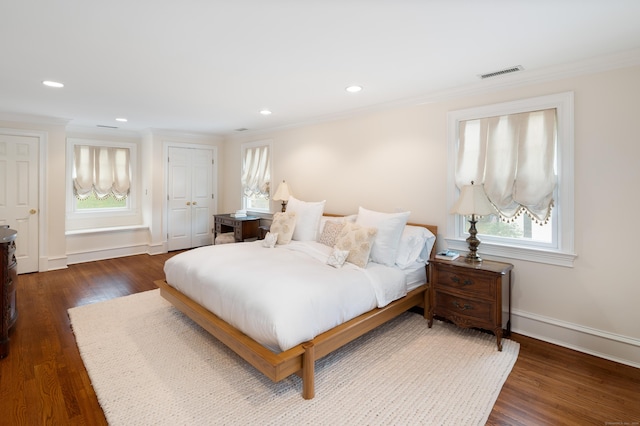 bedroom featuring a closet, dark hardwood / wood-style flooring, crown molding, and multiple windows