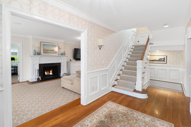 stairway with hardwood / wood-style floors and crown molding