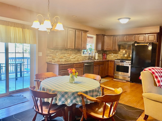 kitchen featuring stainless steel appliances, sink, decorative light fixtures, light hardwood / wood-style floors, and tasteful backsplash