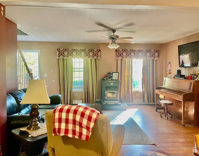 living room featuring a wealth of natural light, ceiling fan, light hardwood / wood-style floors, and a wood stove