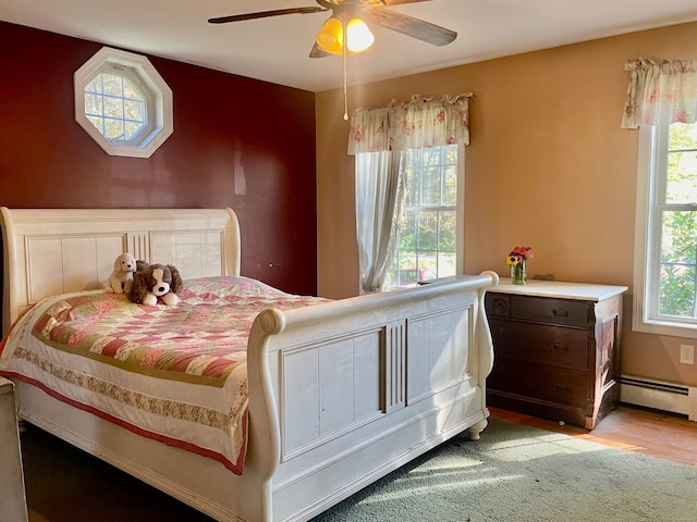 bedroom featuring light hardwood / wood-style floors, multiple windows, a baseboard radiator, and ceiling fan