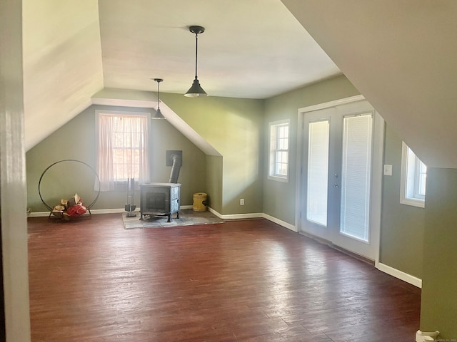 additional living space featuring a healthy amount of sunlight, dark wood-type flooring, and a wood stove