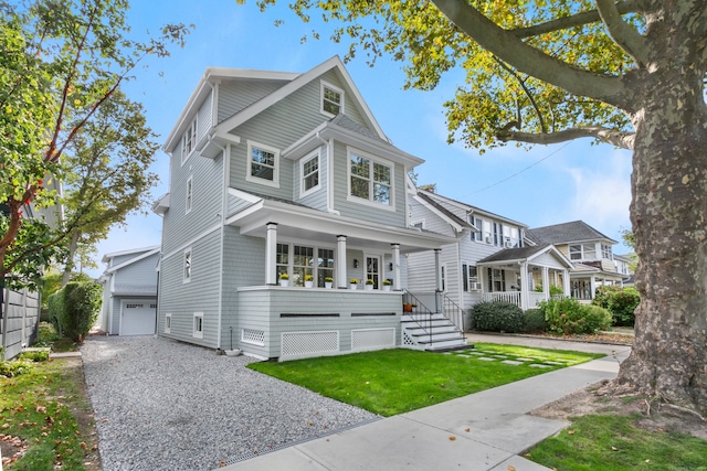 view of front of house featuring covered porch, an outbuilding, a garage, and a front lawn