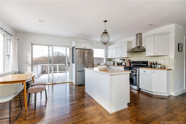 kitchen featuring wall chimney exhaust hood, appliances with stainless steel finishes, and white cabinets