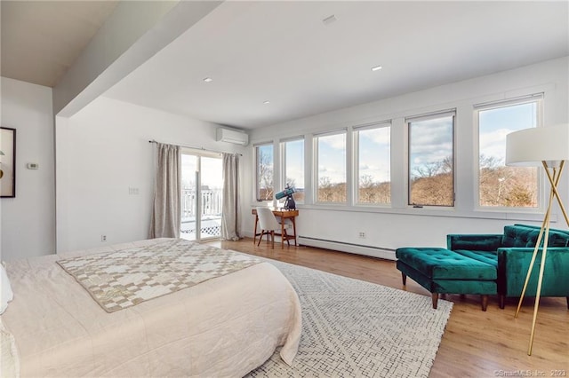 bedroom with a baseboard radiator, multiple windows, light wood-type flooring, and a wall unit AC