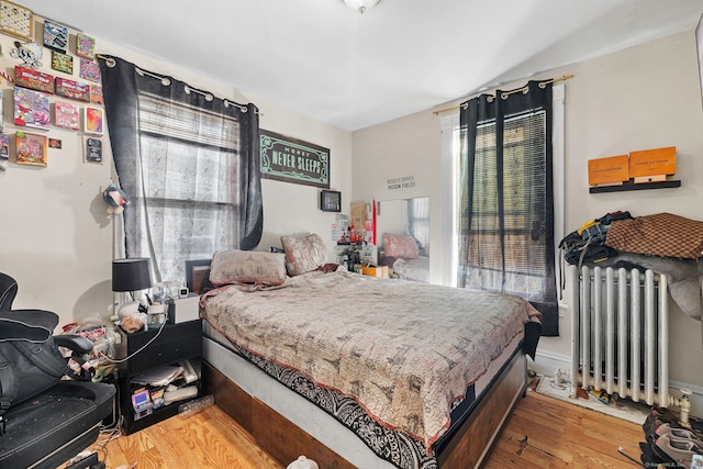 bedroom with hardwood / wood-style floors and radiator heating unit