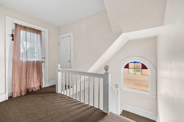 hall with dark carpet and lofted ceiling