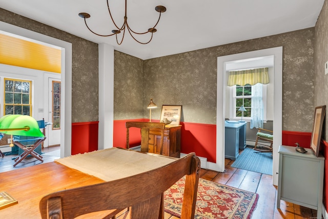 dining room with hardwood / wood-style floors, a chandelier, baseboard heating, wainscoting, and wallpapered walls