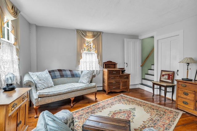 living room with stairway, a baseboard radiator, and hardwood / wood-style flooring