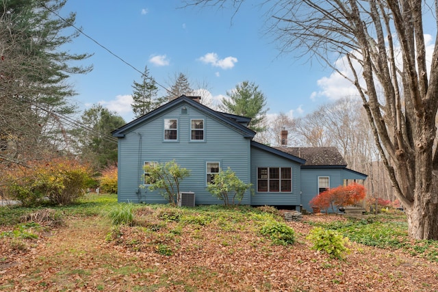 rear view of house with central AC unit and a chimney