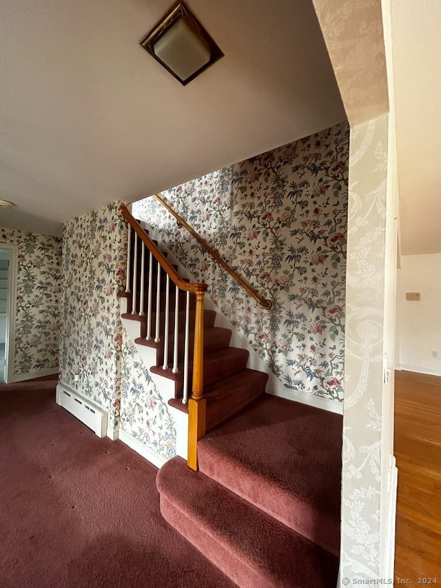 stairway featuring wood-type flooring and a baseboard heating unit