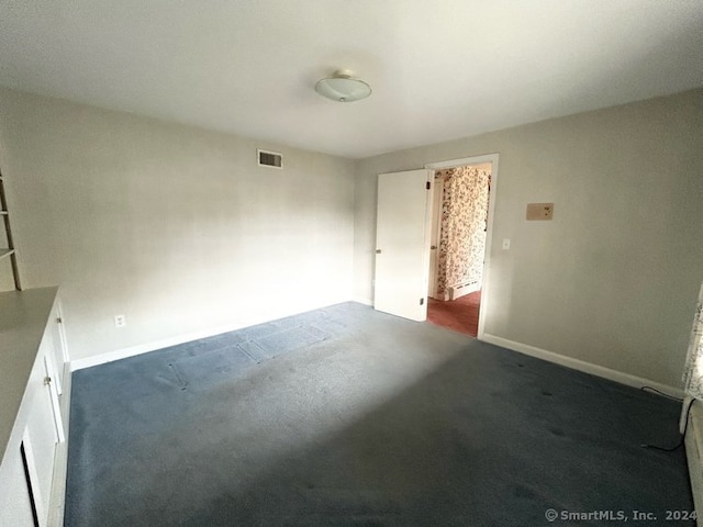 unfurnished room with dark colored carpet