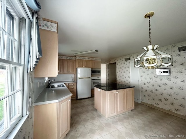 kitchen with white appliances, sink, light brown cabinets, a center island, and hanging light fixtures