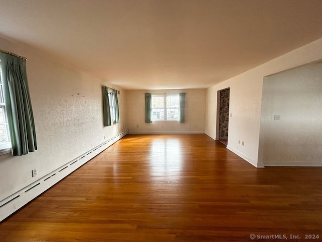 empty room featuring hardwood / wood-style flooring and a baseboard radiator