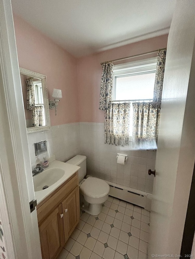 bathroom with vanity, baseboard heating, tile walls, tile patterned flooring, and toilet