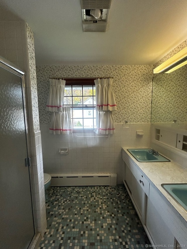 bathroom featuring vanity, baseboard heating, a shower with shower door, and tile walls