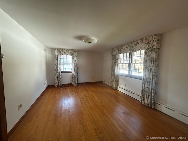 empty room featuring a baseboard heating unit and hardwood / wood-style flooring