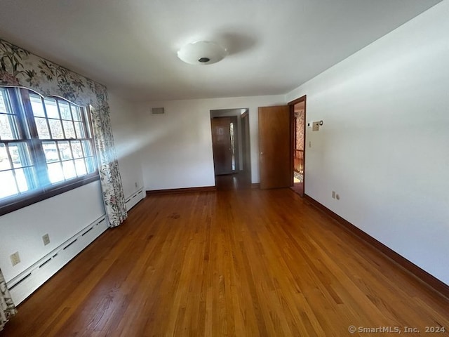 empty room with hardwood / wood-style flooring and baseboard heating