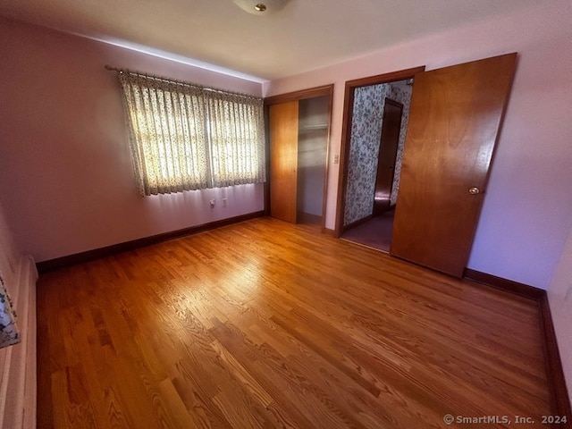 unfurnished bedroom with hardwood / wood-style flooring and a closet