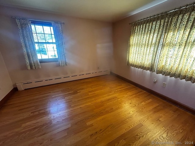 unfurnished room featuring baseboard heating and hardwood / wood-style flooring