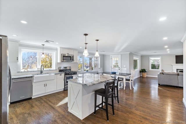 kitchen with appliances with stainless steel finishes, a center island, white cabinetry, and dark wood-type flooring