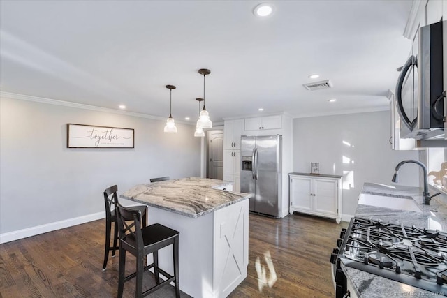 kitchen featuring dark wood-type flooring, a center island, white cabinets, and stainless steel appliances