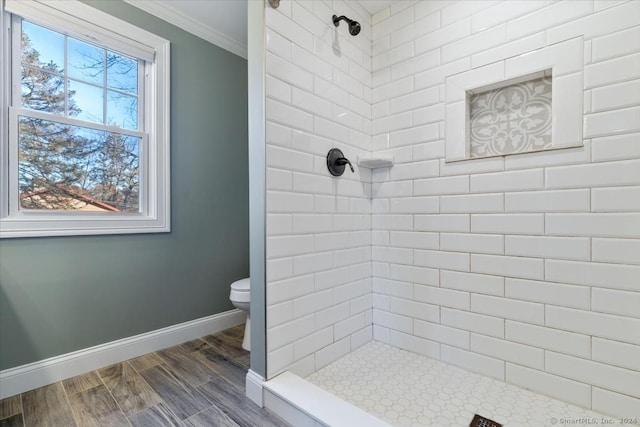 bathroom with crown molding, hardwood / wood-style floors, a healthy amount of sunlight, and toilet