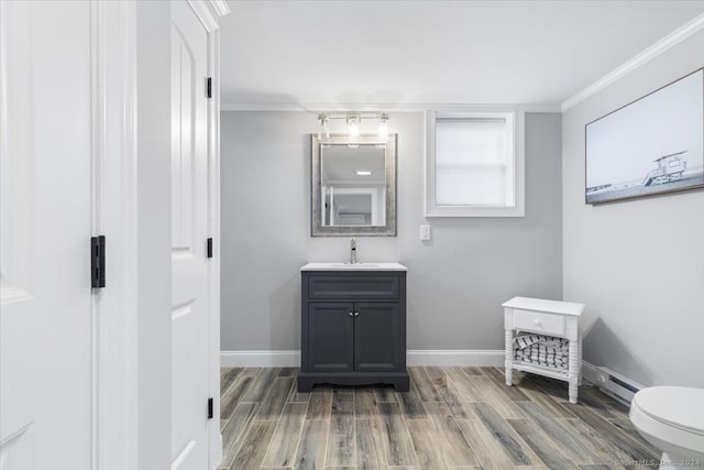 bathroom featuring baseboard heating, hardwood / wood-style floors, toilet, vanity, and ornamental molding