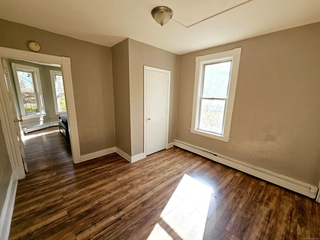 unfurnished bedroom featuring dark hardwood / wood-style flooring and baseboard heating